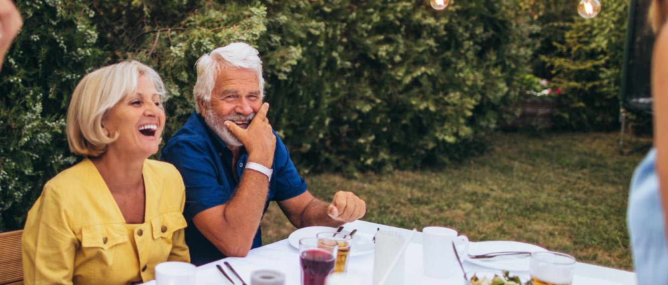 A mature couple laughing at an outdoor dinner