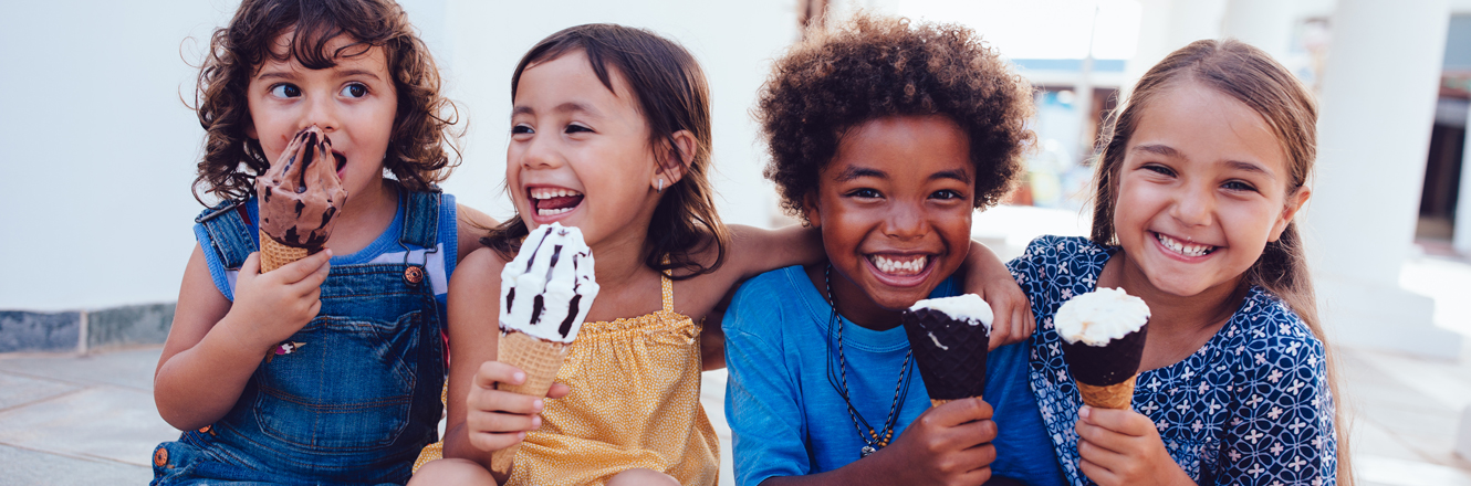 group of kids laughing and eating ice cream in summertime 